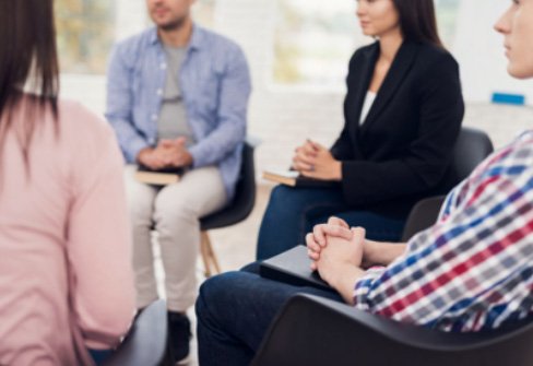 Group of adults sitting on chairs in a circle in a discussion