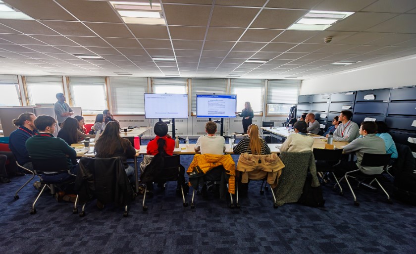 20 young planner sitting around a table looking at a screen