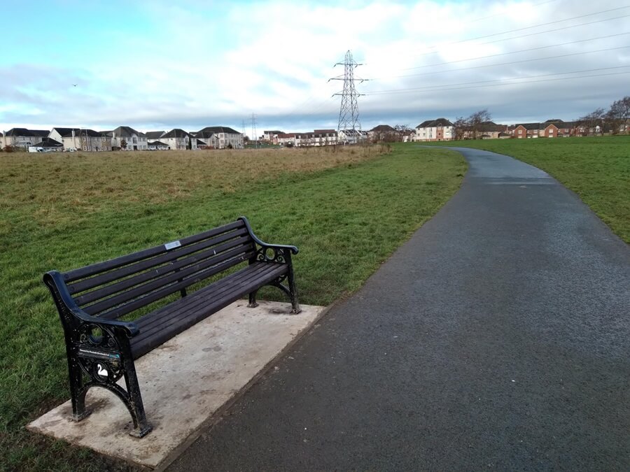 Path through Duloch park with a bench at the side of the path