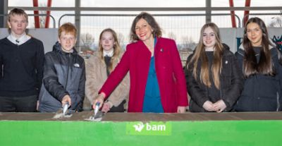 Cllr Carah Hilton with Inverkeithing High School pupils laying cement plinth to mark reaching the highest point of the build.