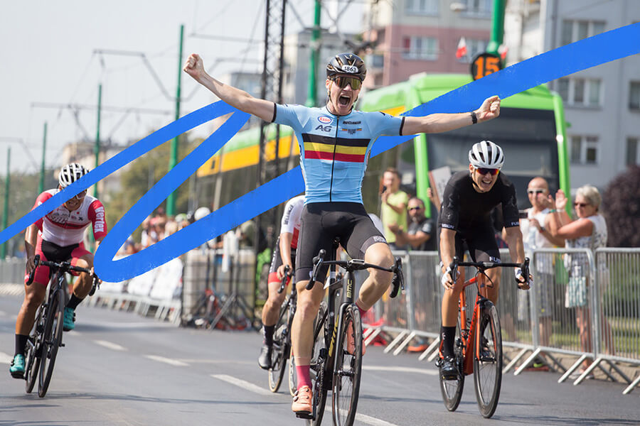 UCI road race cyclist with arms raised crossing finished line.