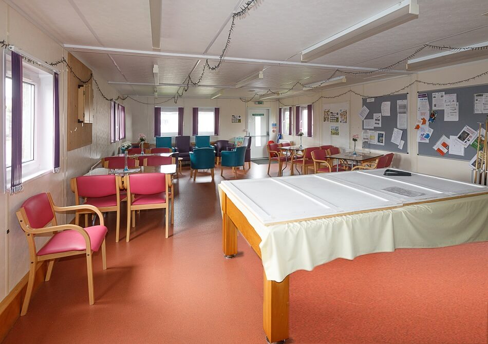 Slightly different angle of internal communal area, with pool table and several tables and chairs set up