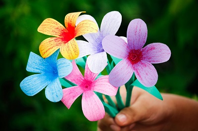 A hand holding a bunch of colourful paper flowers