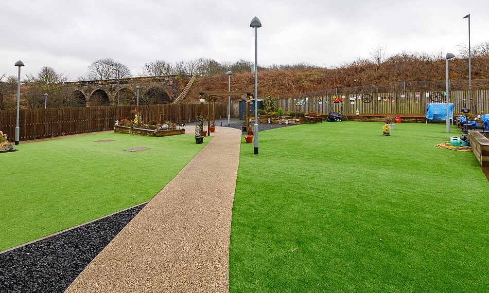 Communal gardens at Den Court, with decking and seating area and railway bridge in the background
