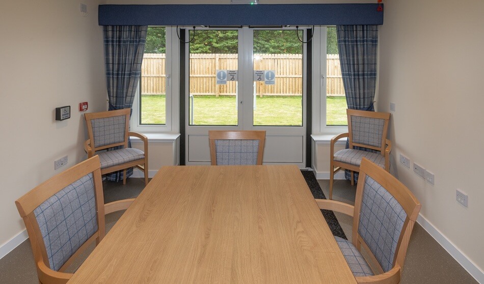 Communal dining room at Lathalmond Square, with tables and chairs looking out into the garden
