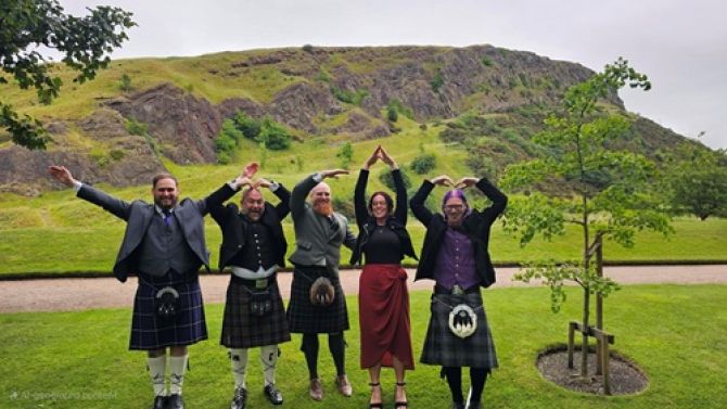 Five people standing in a park creating the letters YMCA with their arms