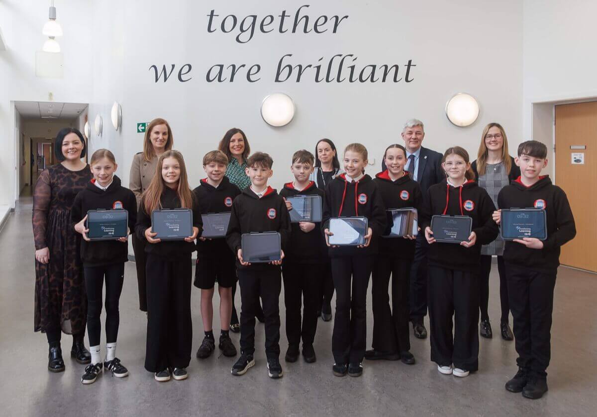 Carnegie PS Group of students and adults standing together indoors holding awards, with the words ‘together we are brilliant’ on the wall behind them.