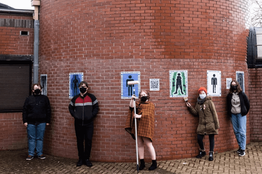 Image of young people in front of a wall covered in art
