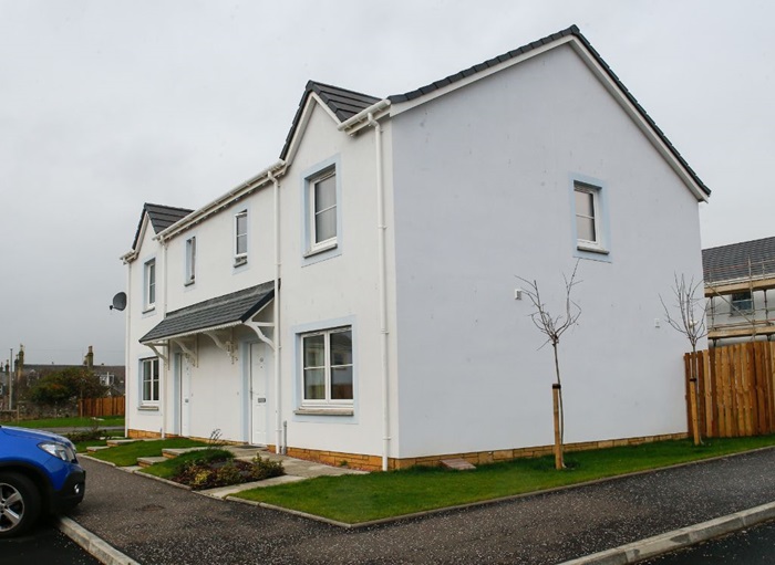 Modern white semi‑detached house with a small front garden and driveway on a residential street.