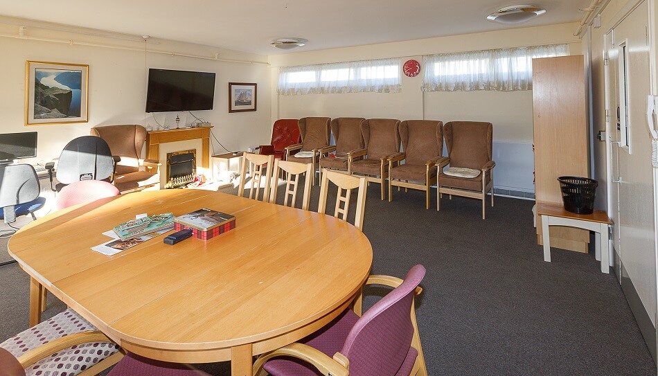 Communal lounge at Sunnyside Court, with dining table and armchairs