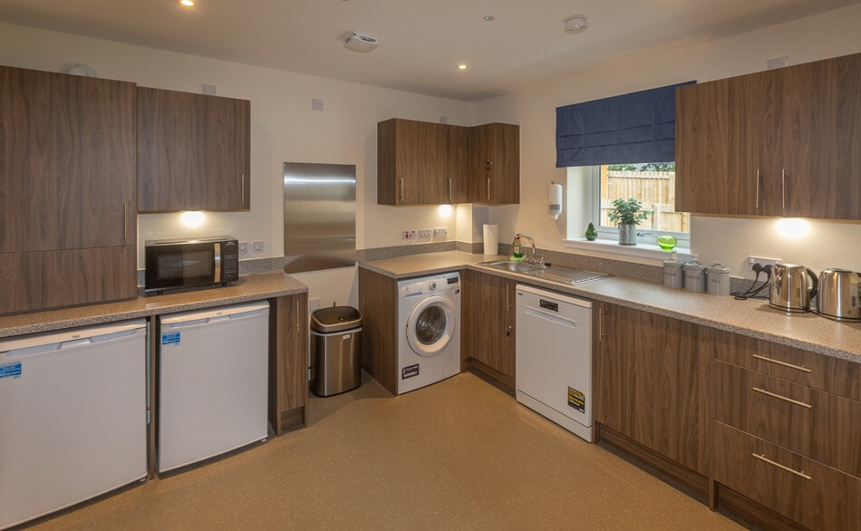 Communal kitchen with brown wood doors and white appliances