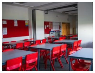 A classroom with desks and red chairs