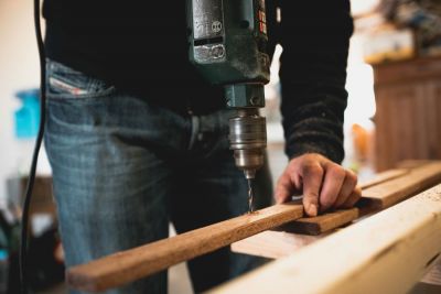 zoomed in image showing someone drilling a hole in a length of wood, with an electric drill