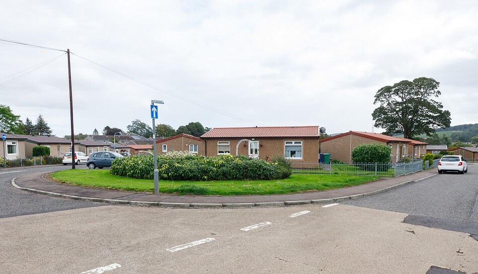 Exterior view of Blalowan Park, showing grassy area and small road in front.