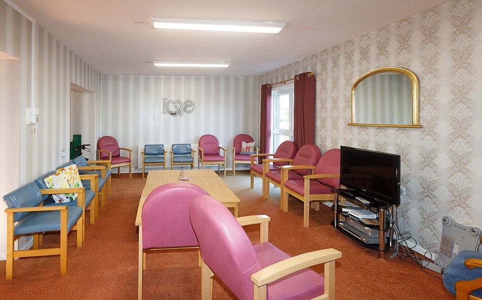 Communal seating area at Moir Court, with armchairs and a coffee table facing a TV