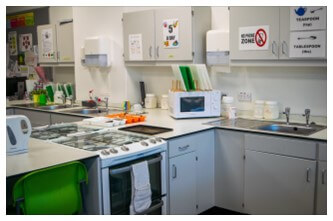 A kitchen with white cabinets and white appliances used as a teaching kitchen