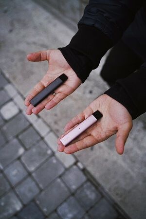 Person with upturned hands each holding a vape 