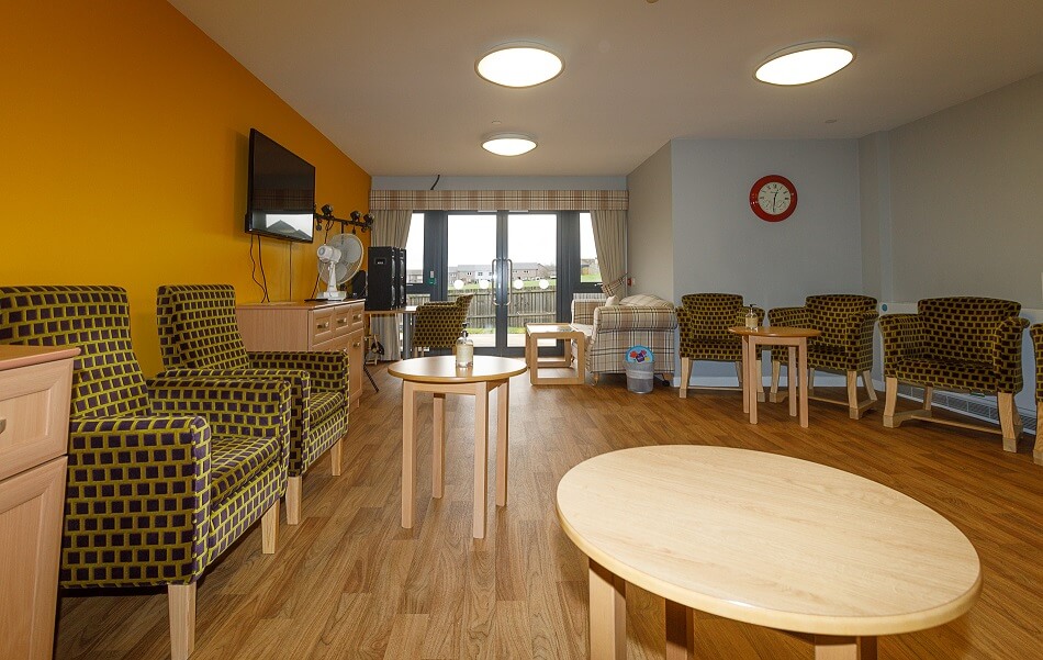Communal seating area with armchairs and tables at Cedar House