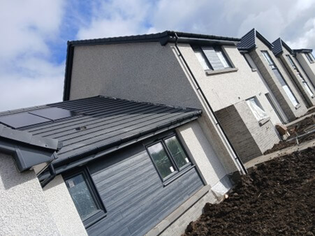 Close up of a set of white and grey houses with dark grey wooden cladding