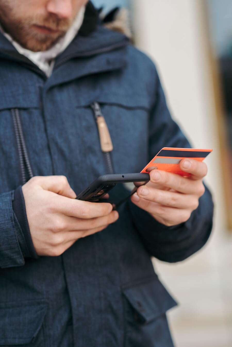 Man holding bank card and mobile phone, making an online payment