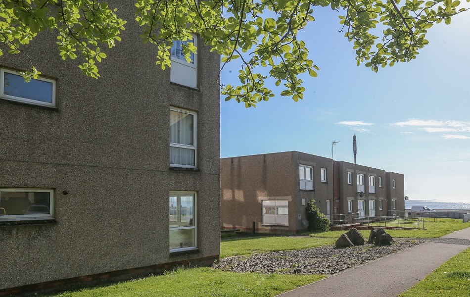 Outer buildings of the Buchanan Court complex, with trees and grassy area
