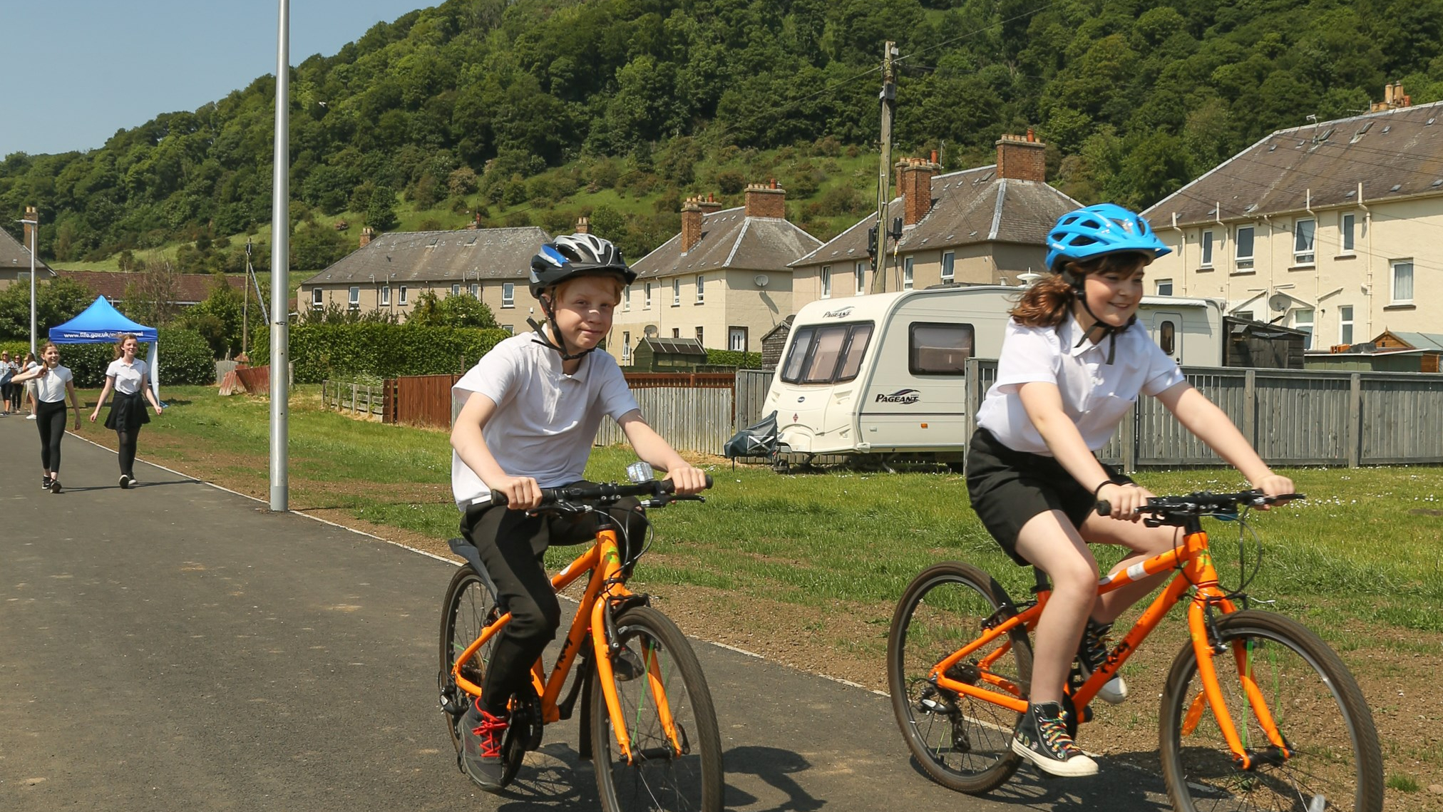Two school children cycling to school on an active travel multi-use path.