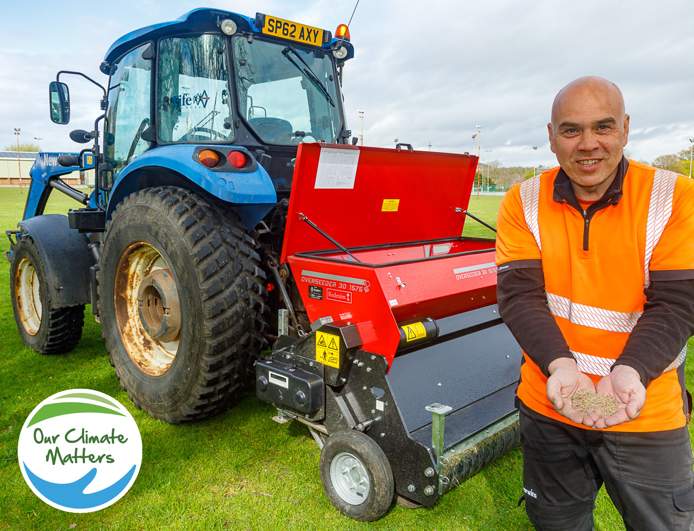 Man standing next to tractor and seed spreader