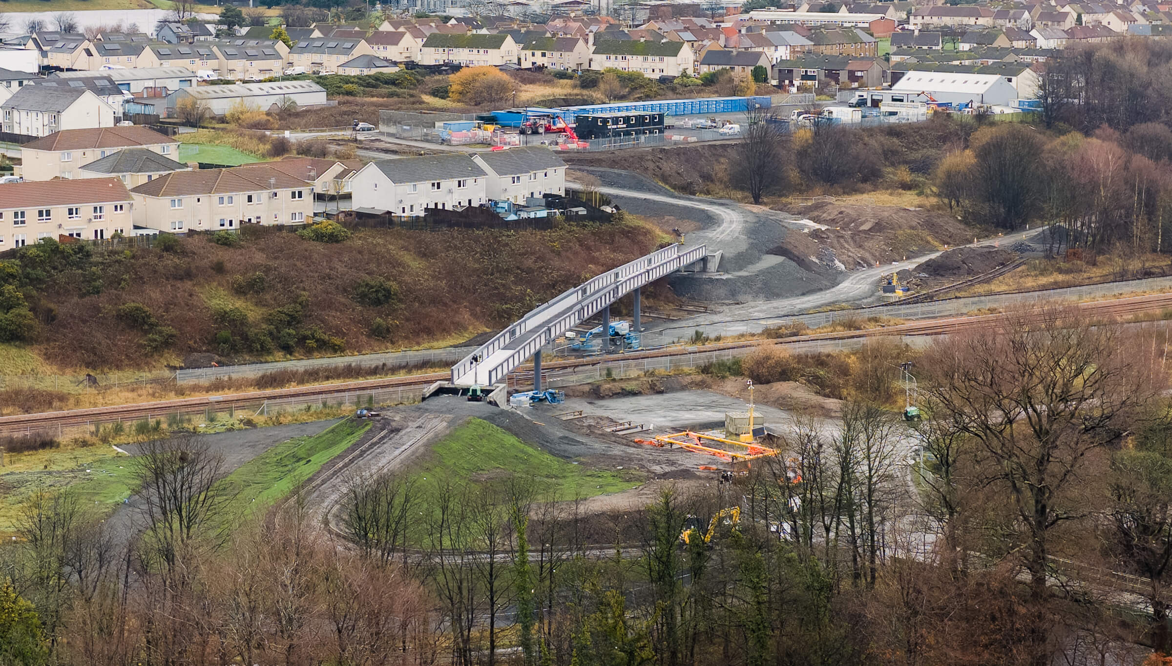 Construction site with the new Mountfleurie pedestrian bridge over railway tracks, surrounded by houses and roads.