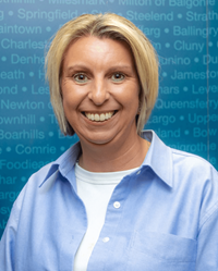 Cllr Zoe Hisbent Councillor Zoe Hisbent wearing a light blue shirt standing in front of a blue background with place names.