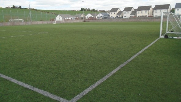  A green football pitch is visible. White lines mark the pitch. Houses are in the background