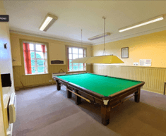 Room with yellow walls and a snooker table in the middle