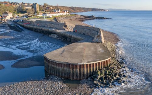Dysart harbour structure with a concrete pier and sea wall beside a pebble beach. - Repair work to begin on Dysart Harbour sea wall