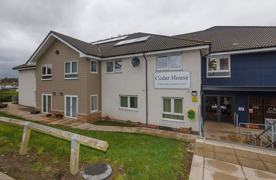 Front of the main building at Cedar House, painted in tan, white and dark blue