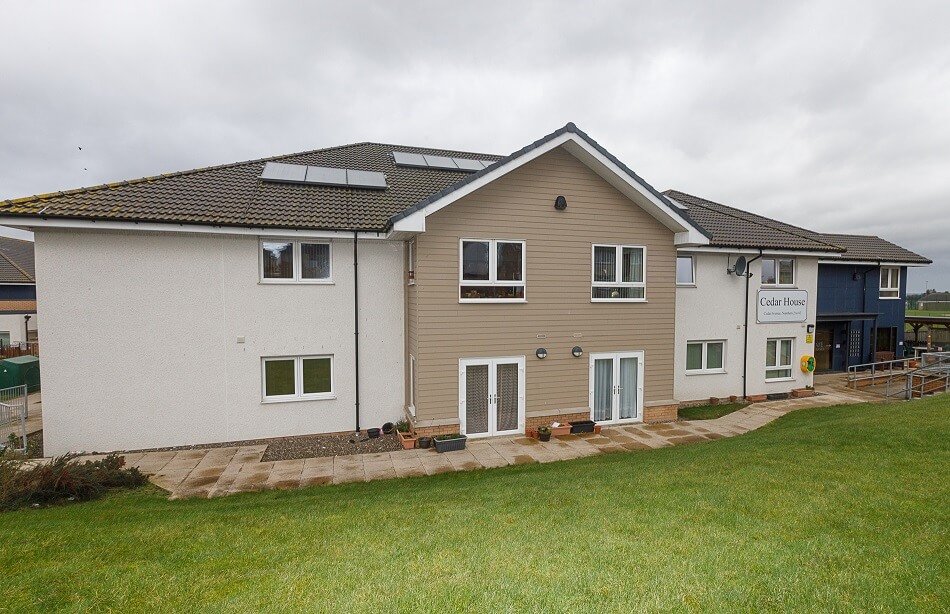 Main building at Cedar House. with large grassy area to the front