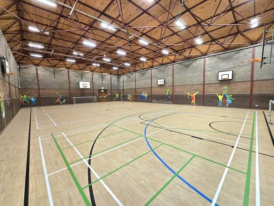 A bright image of valleyfield games hall showing court marking, basketball hoops and goals